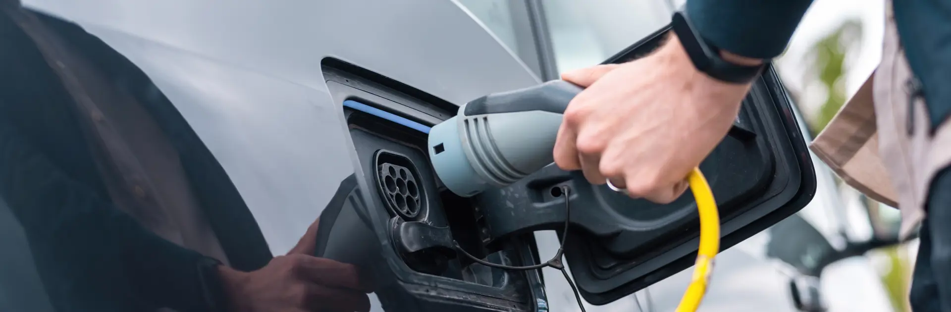 Man Plugging Charger Into Electric Car Charge Station